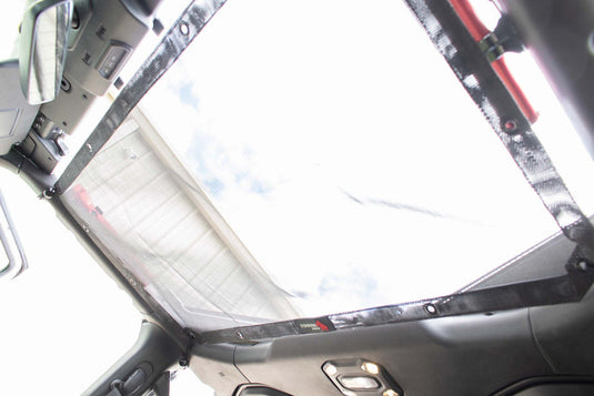 inchInstallation view of Fishbone Offroad sun shade on Jeep Wrangler JL interior, blocking sunlight above dashboardinch