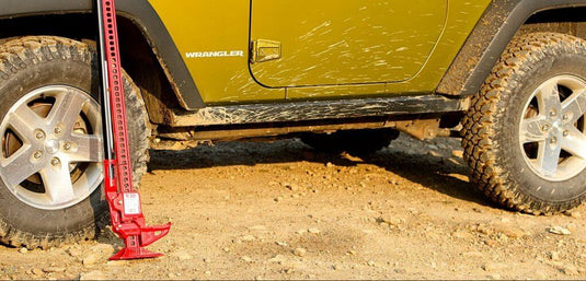 Red Hi-Lift Jack 42 Cast/Steel model supporting a yellow Wrangler's side, demonstrating its utility in an off-road environment.