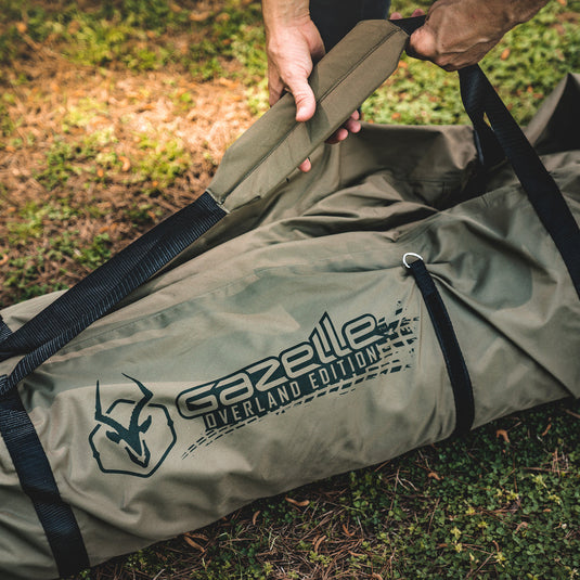 Alt text: inchPerson holding the durable, water-resistant Gazelle T3X Overland Edition Duffle Bag in an outdoor setting, showcasing its sturdy handles and spacious design.inch