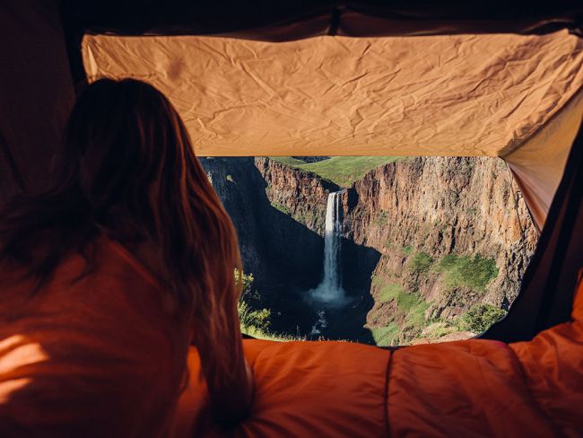 Load image into Gallery viewer, Woman enjoying scenic view from inside a Front Runner Roof Top Tent overlooking a waterfall