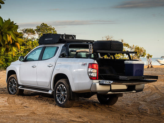 White pickup truck equipped with Front Runner Load Bed Cargo Slide, extended on beach setting.