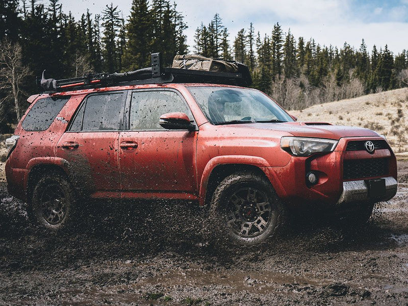 Load image into Gallery viewer, Red Toyota 4Runner with Slimline II Roof Rack Kit by Front Runner on a muddy off-road terrain