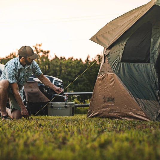 Man setting up a Gazelle Tents T4 Hub Tent Overland Edition at campsite during dusk