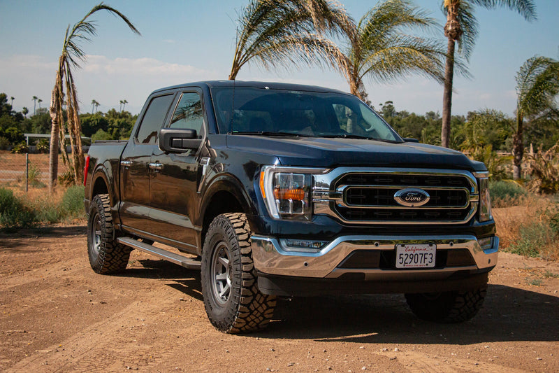 Load image into Gallery viewer, Black Ford truck with ICON Vehicle Dynamics Rebound PRO satin black wheels parked outdoors.