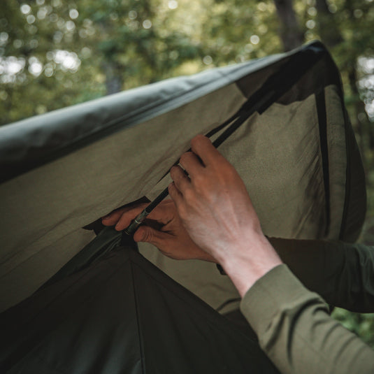 Person setting up Gazelle Tents T4 Hub Tent in forested campsite.