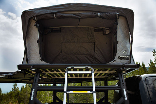 Alt text: "Freespirit Recreation Odyssey Series Black Top Hard Shell Rooftop Tent mounted on vehicle in outdoor setting"