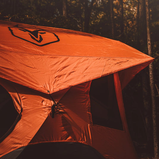Orange Gazelle T4 Hub tent pitched in a forest setting, highlighting the spacious design and easy setup.