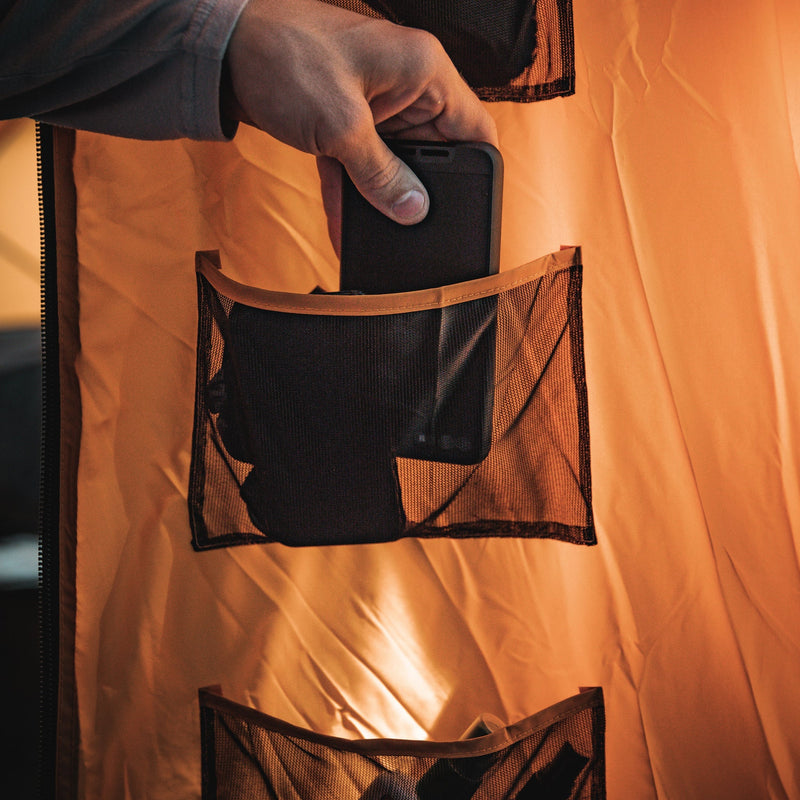 Load image into Gallery viewer, Person storing a smartphone in the Gazelle Tents T8 Hub Tent&#39;s convenient storage pocket.
