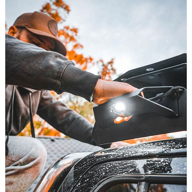 Load image into Gallery viewer, Person installing a Front Runner Handle/Light Slimsport Rack Bracket on vehicle roof rack with illuminated light
