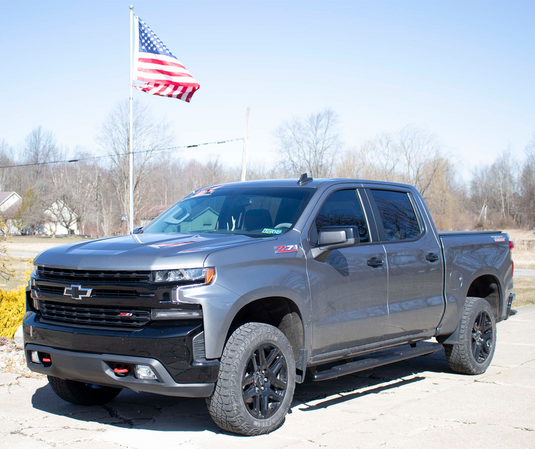 Chevy Silverado Double Cab with installed Fishbone Offroad 5 Inch Oval Side Steps under American Flag