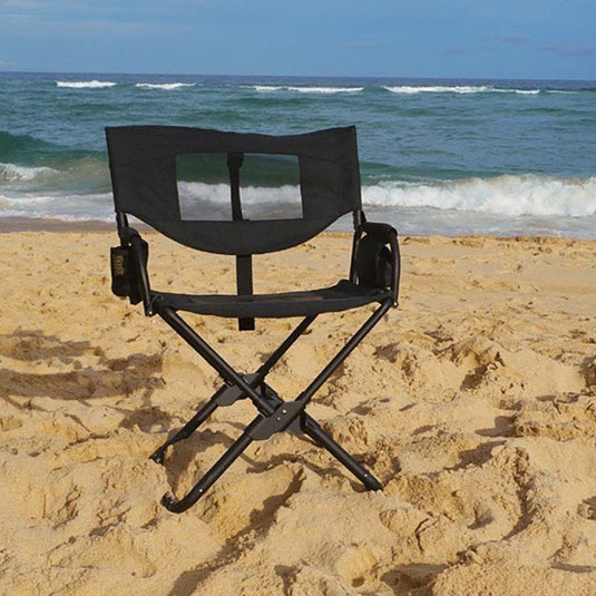 Front Runner Expander Camping Chair on sandy beach with ocean background