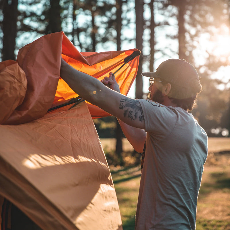 Load image into Gallery viewer, Man setting up Gazelle T8 Hub Tent in forest at sunset
