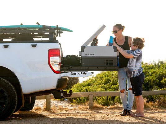 Woman and child accessing cooler on Front Runner Load Bed Cargo Slide in truck bed at the beach.