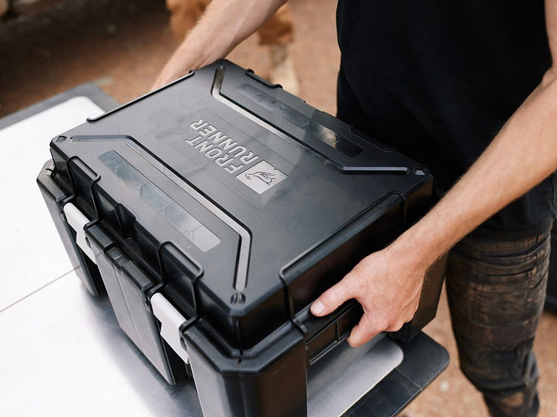 Load image into Gallery viewer, Person securely closing a Front Runner Wolf Pack Pro Hi-Lid storage box outdoors.
