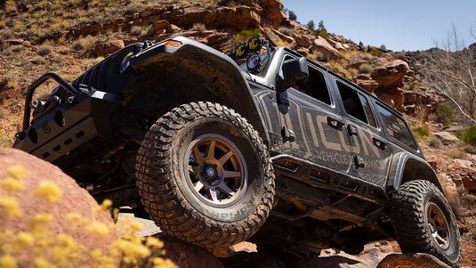Off-road vehicle equipped with ICON Vehicle Dynamics Rebound PRO wheels in Satin Black navigating rocky terrain.