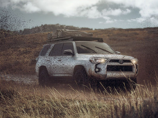 Toyota 4Runner equipped with Front Runner Slimline II Roof Rack driving on rough terrain showing durability and storage capability.