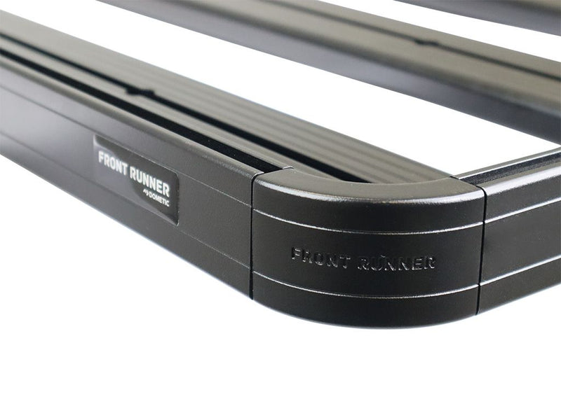 Load image into Gallery viewer, Close-up of Front Runner Slimline II roof rack kit for Land Rover Defender 130 with visible logo and black finish.
