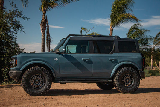 Blue off-road SUV equipped with ICON Vehicle Dynamics Six Speed Satin Black wheels parked outdoors with palm trees in background.