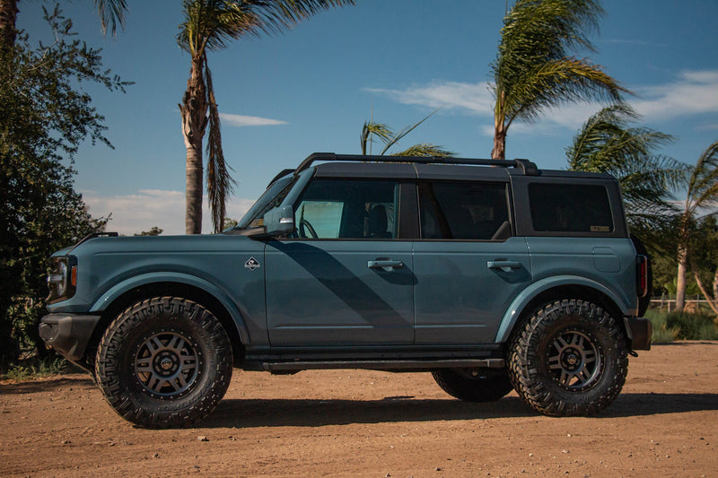 Load image into Gallery viewer, SUV equipped with ICON Vehicle Dynamics Six Speed gunmetal wheels with black ring, off-road tires, parked outdoors with palm trees in the background.
