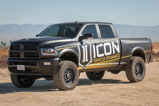 Black Dodge truck with ICON Vehicle Dynamics Alpha graphics and black ring off-road wheels parked in desert terrain