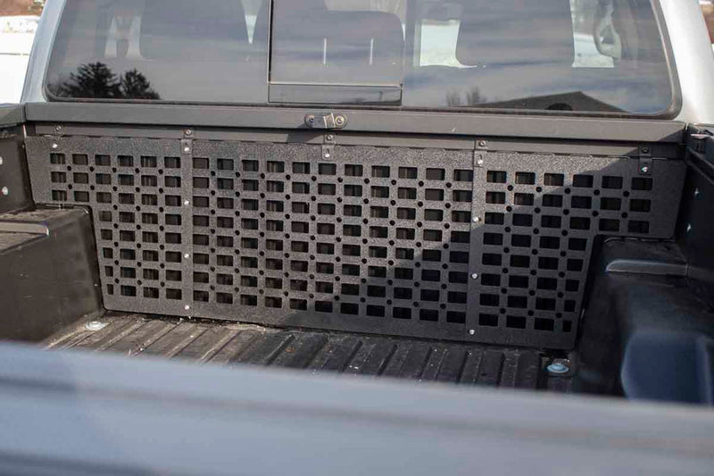 Load image into Gallery viewer, Alt text: &quot;Black Fishbone Offroad Molle Panel installed on the front bed wall of a 2016-2023 Toyota Tacoma, showing compatibility and fit.&quot;

