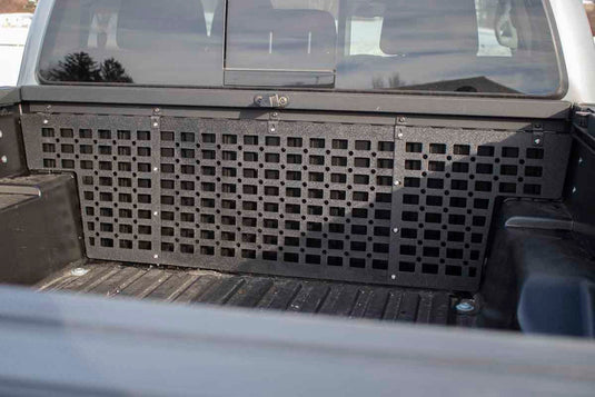 Alt text: "Black Fishbone Offroad Molle Panel installed on the front bed wall of a 2016-2023 Toyota Tacoma, showing compatibility and fit."
