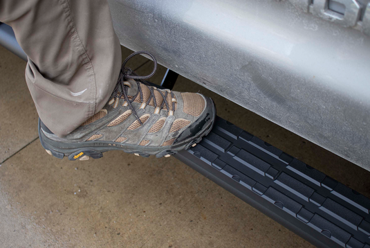 Person stepping onto black 5 inch oval Fishbone Offroad side step for Toyota Tundra Crew Max Cab.