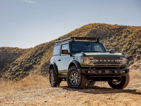"2022 Ford Bronco 2 Door with Front Runner Slimline II Roof Rack Kit installed, parked on rugged terrain under clear skies"