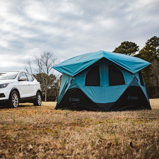 Alt text: inchGazelle Tents T3X Overland Edition Tent set up in a field with a white SUV parked beside it, showcasing the tent’s spacious design suitable for car camping and outdoor adventures.inch