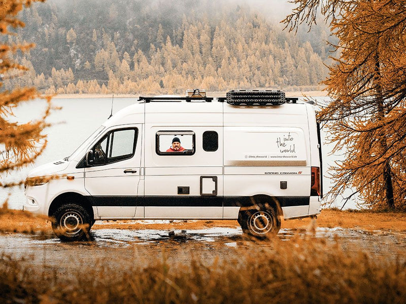 Load image into Gallery viewer, Mercedes Benz Sprinter with Slimline II Roof Rack Kit parked by a lake surrounded by autumn trees
