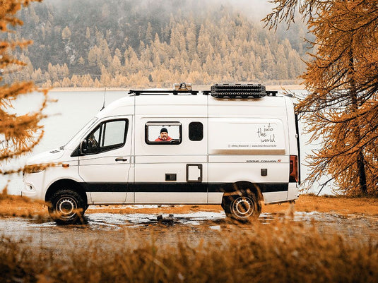 Mercedes Benz Sprinter with Slimline II Roof Rack Kit parked by a lake surrounded by autumn trees
