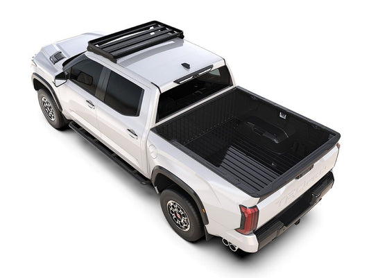 White Toyota Tundra with Front Runner Slimline II Roof Rack Kit installed, angled view showcasing cab-over camper configuration.