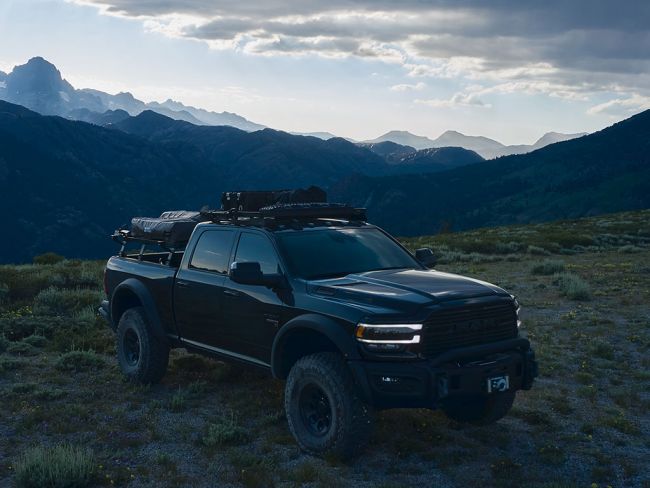 Load image into Gallery viewer, Front Runner Ram 1500 6.4-foot Slimline II Load Bed Rack Kit on a pickup truck against mountainous backdrop during sunset

