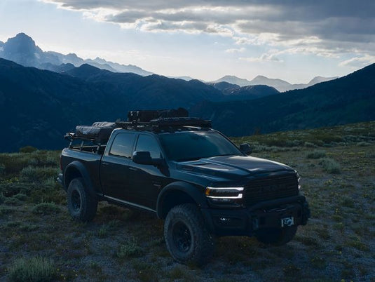 Front Runner Ram 1500 6.4-foot Slimline II Load Bed Rack Kit on a pickup truck against mountainous backdrop during sunset