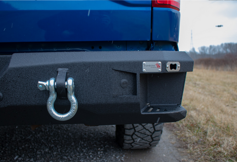 Load image into Gallery viewer, Fishbone Offroad logo on Pelican Rear Bumper for 2015-Current Ford F-150 with tow hook detail.
