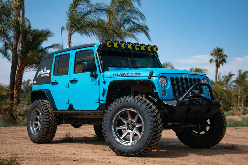 Load image into Gallery viewer, Blue off-road vehicle with ICON Vehicle Dynamics Bandit Gloss Bronze rims parked outdoors.
