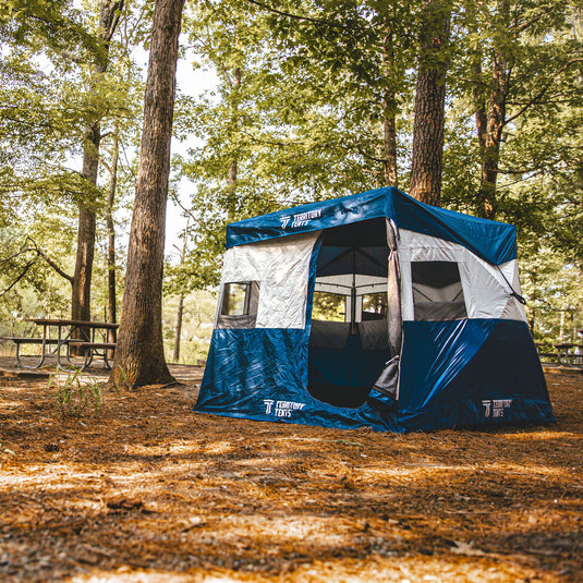 Alt text: "Territory Tents Jet Set 3 Hub Tent set up in a forest campground with trees in the background, highlighting spacious design and durable material."