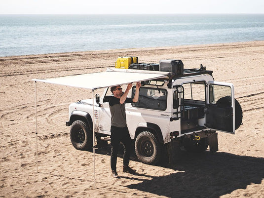 Front Runner Easy-Out Awning 1.4M attached to off-road vehicle on beach providing shade