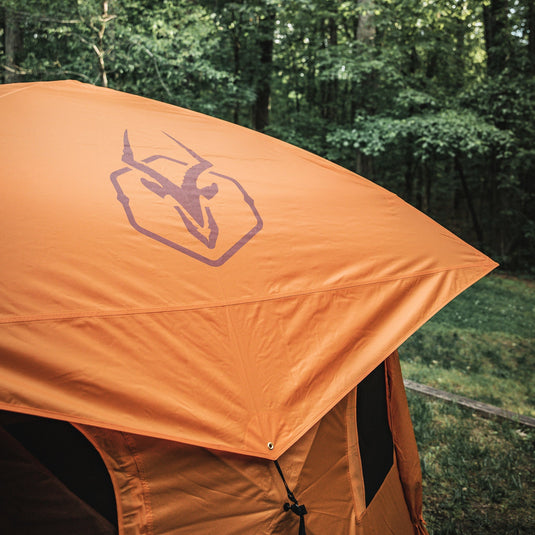 Orange Gazelle Tents T4 Hub Tent Overland Edition set up in a forested area with the brand's logo visible on the canopy.