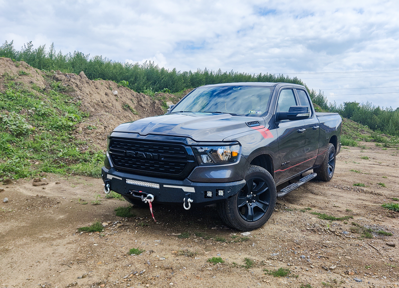 Load image into Gallery viewer, Alt text: &quot;2019-2023 Ram truck with Fishbone Offroad Pike Front Bumper installed, parked offroad showcasing rugged design and durability.&quot;
