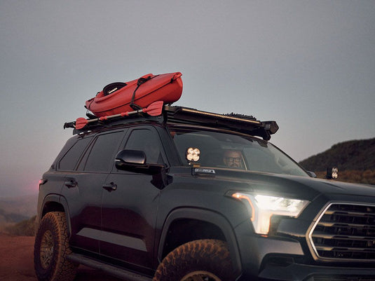 Front Runner Toyota Tundra with mounted Front Runner ditch light brackets and roof rack carrying a kayak at dusk