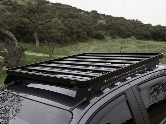 Front Runner GMC Canyon 2015-current Slimline II roof rack kit installed on vehicle outdoors with nature backdrop.