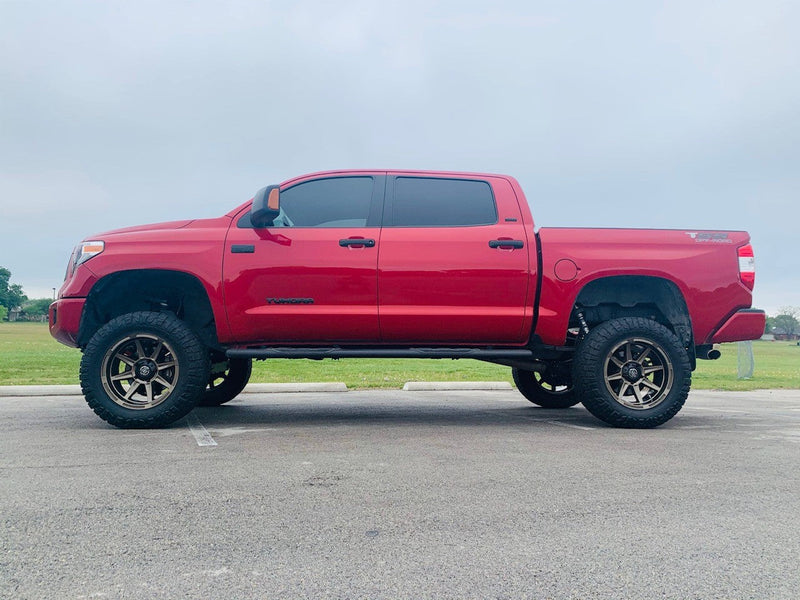 Load image into Gallery viewer, Red pickup truck equipped with ICON Vehicle Dynamics Bandit Gloss Bronze wheels parked outdoors.
