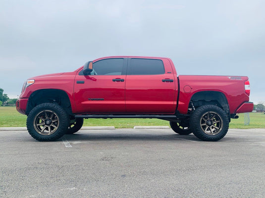 Red pickup truck equipped with ICON Vehicle Dynamics Bandit Gloss Bronze wheels parked outdoors.