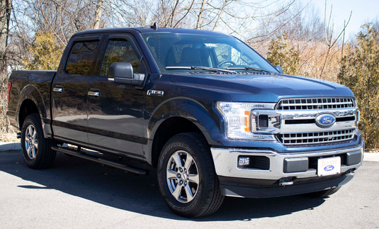 Alt text: "2015-2023 Ford F-Series SuperCrew pickup with Fishbone Offroad 5-inch oval side steps installed for easy entry."
