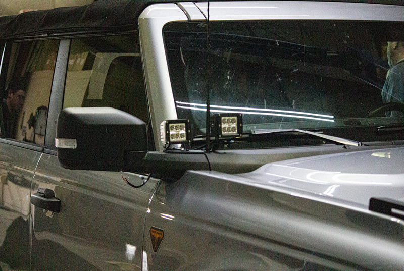 Load image into Gallery viewer, Fishbone Offroad cowl pod light brackets mounted on 2022 Ford Bronco, LED lights attached to vehicle exterior next to windshield.
