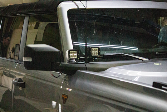 Fishbone Offroad cowl pod light brackets mounted on 2022 Ford Bronco, LED lights attached to vehicle exterior next to windshield.
