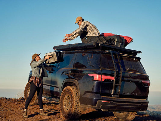 Two people using Front Runner ladder to access roof rack on a 2023 Toyota Sequoia off-road vehicle