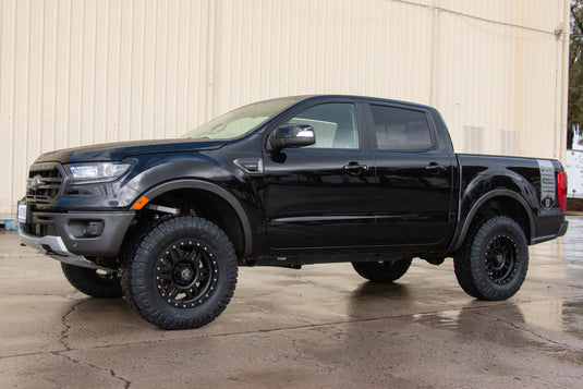 Black pickup truck equipped with ICON Vehicle Dynamics Six Speed Satin Black wheels parked outdoors.