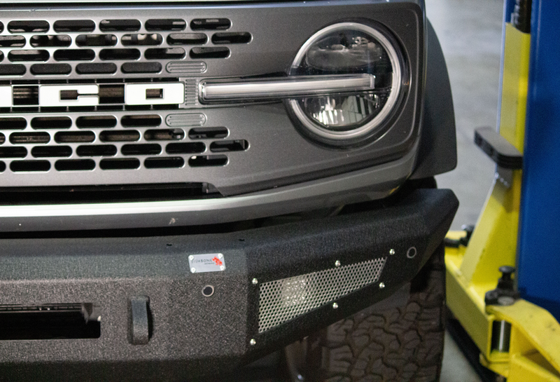 Load image into Gallery viewer, Alt text: &quot;Close-up of a Fishbone Offroad 2022-Current Ford Bronco Steelhead Front Bumper installed on a vehicle, showcasing the bumper&#39;s texture and design details.&quot;
